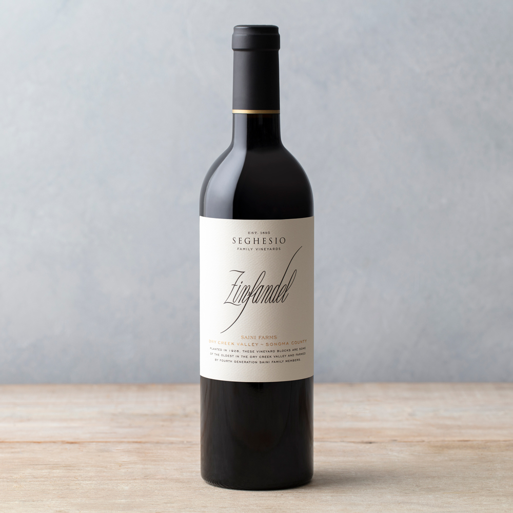 Saini Farms Zinfandel wine bottle on wood table with grey background